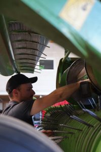 Mitarbeiter führt eine Wartung an der Pickup-Einheit einer landwirtschaftlichen Maschine durch.