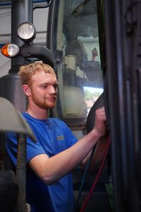 Junger Mitarbeiter des Lohnbetriebs Bohmann arbeitet konzentriert an einer landwirtschaftlichen Maschine.