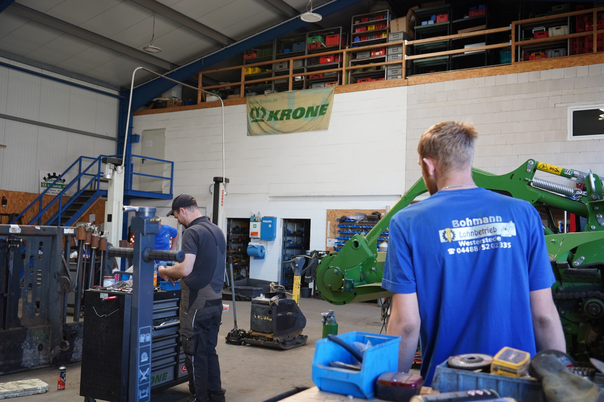 Zwei Mitarbeiter des Lohnbetriebs Bohmann arbeiten an verschiedenen Stationen in einer gut ausgestatteten Werkstatt.