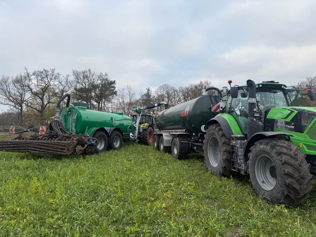 Zwei Traktoren mit Güllefässern und Ausbringtechnik auf einer Wiese im landwirtschaftlichen Einsatz.